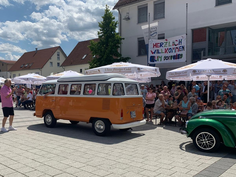 Oldtimer-Parade mit orange-weißem VW Bully